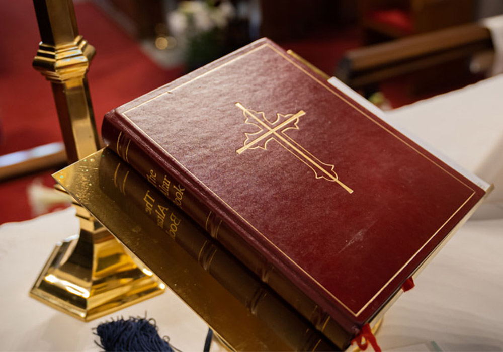 Close-up of a red Book of Common Prayer resting on a brass book stand inside the church.